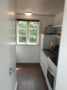 a small kitchen with white appliances and a window at St. Strandbygaard in Åkirkeby