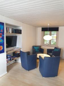 a living room with blue chairs and a table at St. Strandbygaard in Åkirkeby