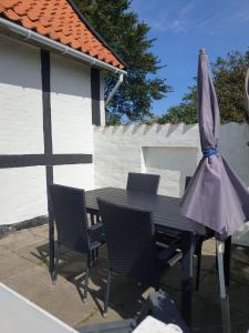a table and chairs with an umbrella on a patio at St. Strandbygaard in Åkirkeby