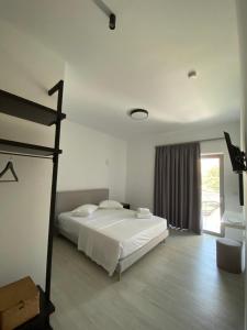 a white bedroom with a bed and a window at elea resort 2 in Preveza