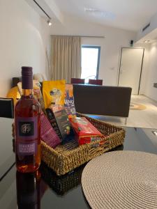 Una botella de vino sentada junto a una cesta de comida. en elea resort 2 en Preveza