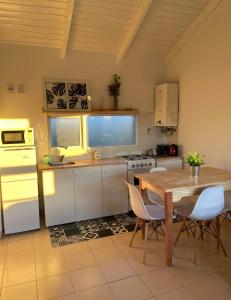 - une cuisine avec une table en bois et des placards blancs dans l'établissement TAAR AIKE II (Lugar de Hielo), à El Calafate