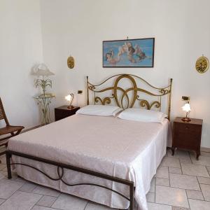 1 dormitorio con 1 cama con sábanas blancas y una pintura en la pared en Casa Vacanze Maria, en Cursi