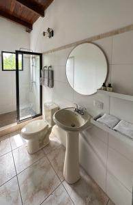 a bathroom with a sink and a toilet and a mirror at Helechos Hotel in Comayagua