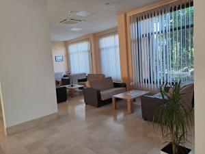 uma sala de espera com sofás, mesas e janelas em Hotel Albamaris em Biograd na Moru
