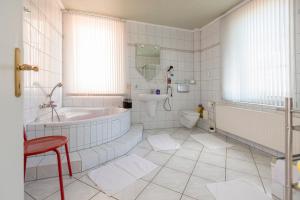 La salle de bains blanche est pourvue d'une baignoire et de toilettes. dans l'établissement Villa Regina Fürstensuite, à Friedrichroda
