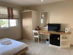 a bedroom with a bed and a desk with a television at บ้านศรีแบริ่ง in Bangna