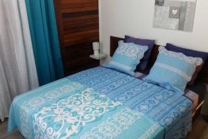 a bed with blue and white sheets and pillows at Le Papyrus in Cilaos