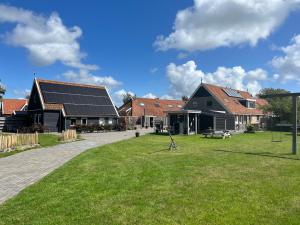 een groep huizen met zonnepanelen op het gras bij De Skuorre in Baaiduinen