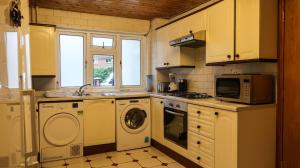 a kitchen with a washing machine and a microwave at Cozy double room - Only room in London
