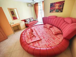 a large red couch in a living room with a table at Boutique Guest House 'Sofia' in Nesebar