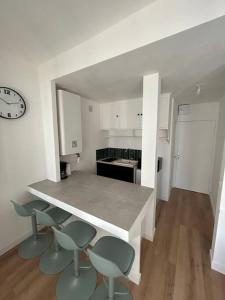 une cuisine avec un comptoir, des chaises et une horloge dans l'établissement La Galerie de Lumière 201, à Aurillac