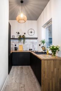 a kitchen with black cabinets and a wooden counter top at Apartament Parkowy przy Stadionie Śląskim Katowice Chorzów in Chorzów +7 photos