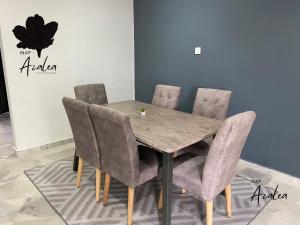 - une table à manger avec des chaises gris dans la chambre dans l'établissement Homestay Azalea, à Cukai
