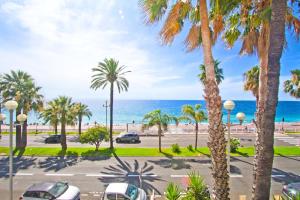 Una vista de un estacionamiento con palmeras y el océano. en Luxury sea front suite Promenade, en Niza