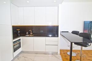 Una cocina con gabinetes blancos y una mesa con sillas. en Luxury sea front suite Promenade, en Niza