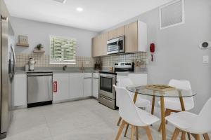 eine Küche mit weißen Geräten sowie einem Tisch und Stühlen in der Unterkunft Sistrunk Shades Villas #1 - Brand New Townhomes Downtown Fort Lauderdale in Fort Lauderdale
