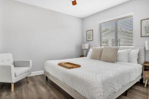 ein weißes Schlafzimmer mit einem Bett und einem Stuhl in der Unterkunft Sistrunk Shades Villas #1 - Brand New Townhomes Downtown Fort Lauderdale in Fort Lauderdale