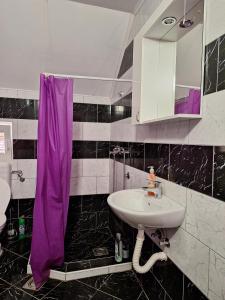 a bathroom with a sink and a purple shower curtain at Apartman Ognjenović in Pluzine