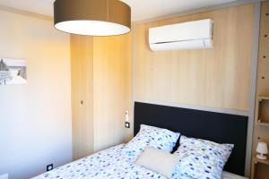 a bedroom with a bed and a ceiling fan at Escales Voyages Cottage des Dunes - Chalet de 49m2 climatisé - 6 personnes in Jullouville-les-Pins