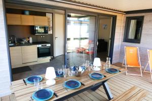 una mesa de madera con placas azules en la cocina en Cottage des Dunes - Chalet de 49m2 climatisé - 6 personnes, en Jullouville-les-Pins