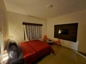 um quarto com uma cama, uma mesa e uma televisão em July17 residency em Kodaikanal