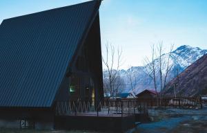 um grande edifício preto com montanhas ao fundo em Cottage GarShemo Kazbegi em Kazbegi
