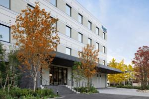 an office building with fall trees in front of it at Fairfield by Marriott Hyogo Awaji Fukura in Minamiawaji