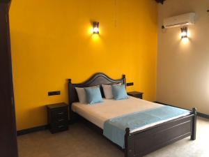 a bedroom with a bed with a yellow wall at Sun Star Villa Negombo in Daluwekotuwa