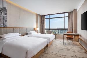 um quarto de hotel com três camas e uma televisão em Four Points by Sheraton Shanghai, Kangqiao em Xangai