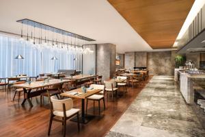um restaurante com mesas e cadeiras de madeira e um bar em Four Points by Sheraton Shanghai, Kangqiao em Xangai