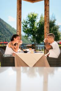 un hombre y una mujer sentados en una mesa comiendo comida en Hostellerie Le Lievre Amoureux, en Valpelline