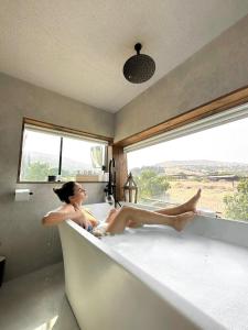a woman sitting in a bath tub with a window at Leobus-לאו באס in Menaẖemya
