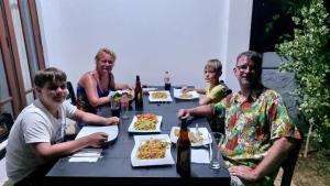 坦加拉的住宿－AMOUR AT TURTLE BEACH，一群人坐在餐桌旁吃着食物
