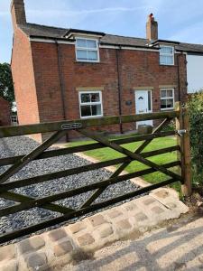 a wooden gate in front of a brick building at Newton Hall farm cottage with amazing views & hot tub in Preston