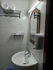 Baño blanco con lavabo y espejo en Al Hedayet International Hotel, en Seeb