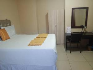 a bedroom with a bed and a desk and a mirror at Beautiful Gate Guesthouse in Palatswe