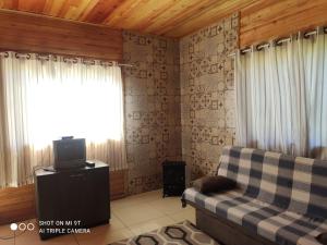 a living room with a couch and a tv at Cabanas das Araucárias in Urubici