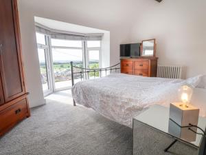 a bedroom with a bed and a tv and a window at Aster Cottage in Rhyl