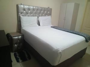 1 cama grande con sábanas y almohadas blancas en Beautiful Gate Guesthouse, en Palapye