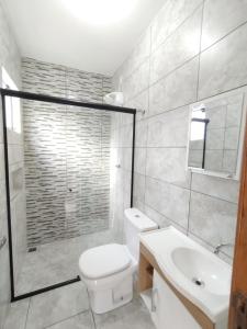 a bathroom with a toilet and a sink and a shower at Suítes do Vale - Praia do Rosa in Imbituba