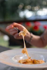 une personne tenant une fourchette avec de la nourriture sur une assiette dans l'établissement Hostellerie Le Lievre Amoureux, à Valpelline