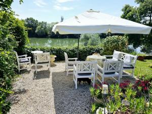 a table and chairs under an umbrella next to a lake at Jan's place in Burgundy in Écuelles
