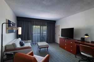 a living room with a couch and a flat screen tv at Courtyard by Marriott Dallas Plano Parkway at Preston Road in Plano