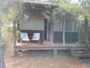 2 chaises assises sur une terrasse couverte d'une maison dans l'établissement la cabanita pinamar, à Pinamar