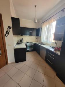 cocina con armarios negros y suelo de baldosa en Nice and friendly apartment, en Elbasan