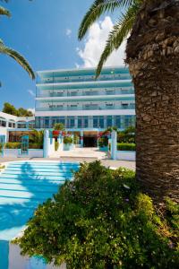 a building with a palm tree in front of it at Belair Beach Hotel in Ixia