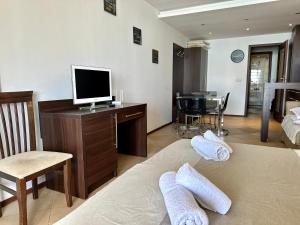 een woonkamer met een televisie en een bureau met een computer bij Home Sweet Home Black Sea View in Balchik