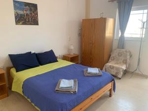 a bedroom with a blue and yellow bed and a chair at Perivoli Guest Rooms in Kokkinos Pirgos