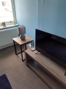 a living room with a flat screen tv and a table at Bank House in Thurso